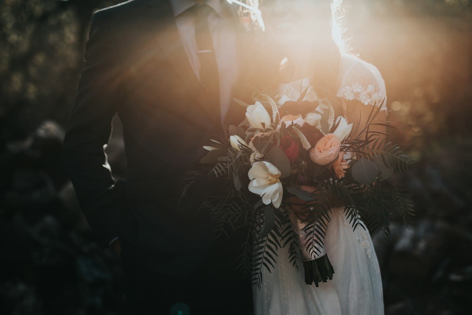 Bride and groom holding a bouquet in the evening sun