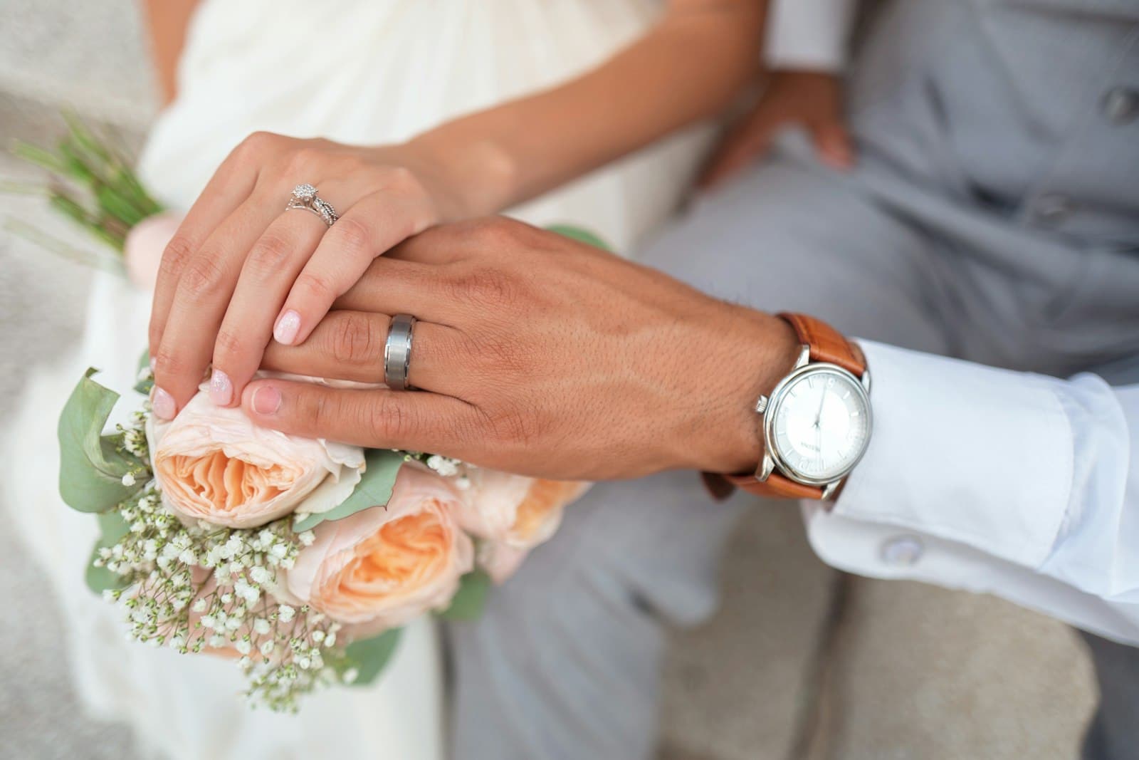 Hands with wedding rings over a rose bouquet
